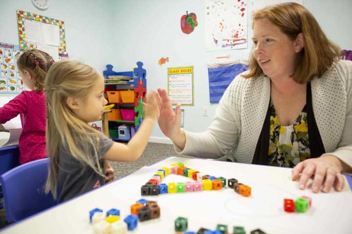 Young child and teacher engaged in a high five at school