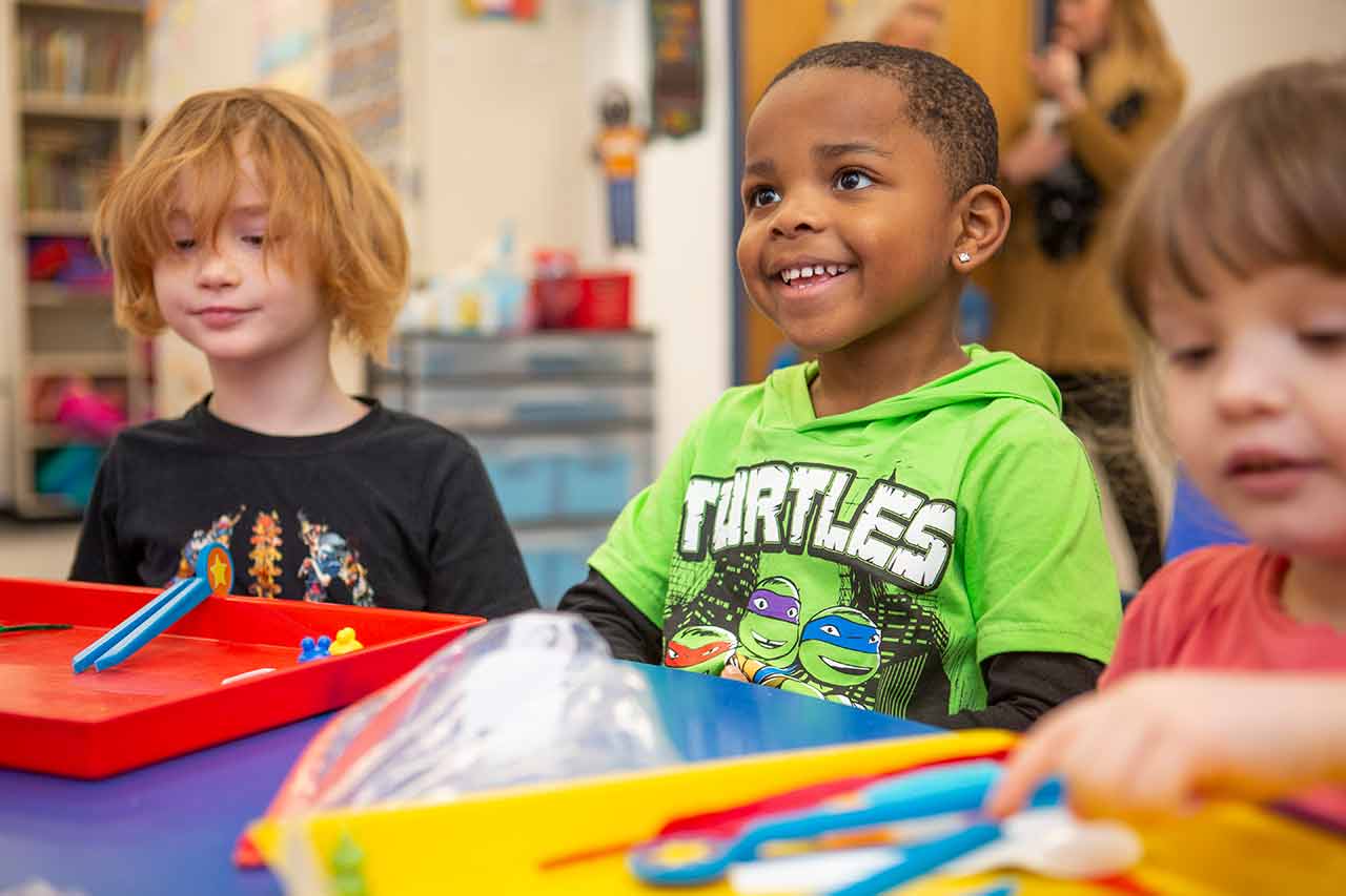 Young boy looking excited about a classroom activity.