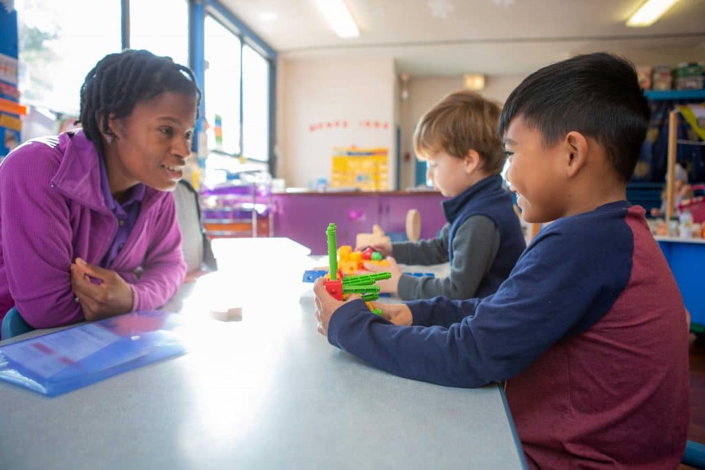 Teacher encouraging a child while he plays with building toy