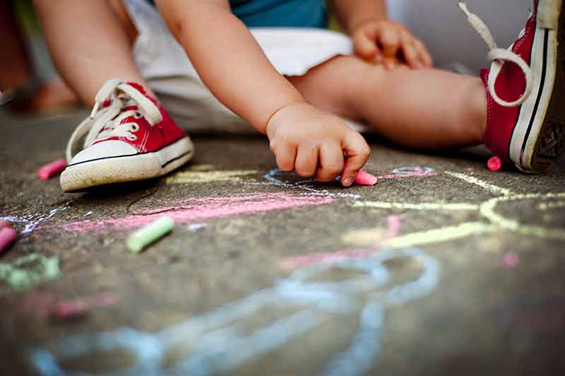 Child drawing on ground with chalk