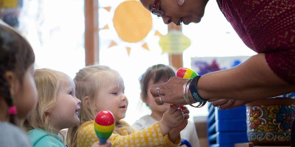An educator showing children how to use a musical instrument